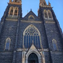20250410_095419 Sharon in front of Saint Patrick's Cathedral. It is an imposing 1800s Gothic Revival–style cathedral, known for its unique bells and ornate stained glass.