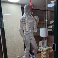 20250423_203641 Here is a unique storefront window dressing. A statue of David, famously sculpted by Michelangelo, playfully adorned with beach-related accessories: